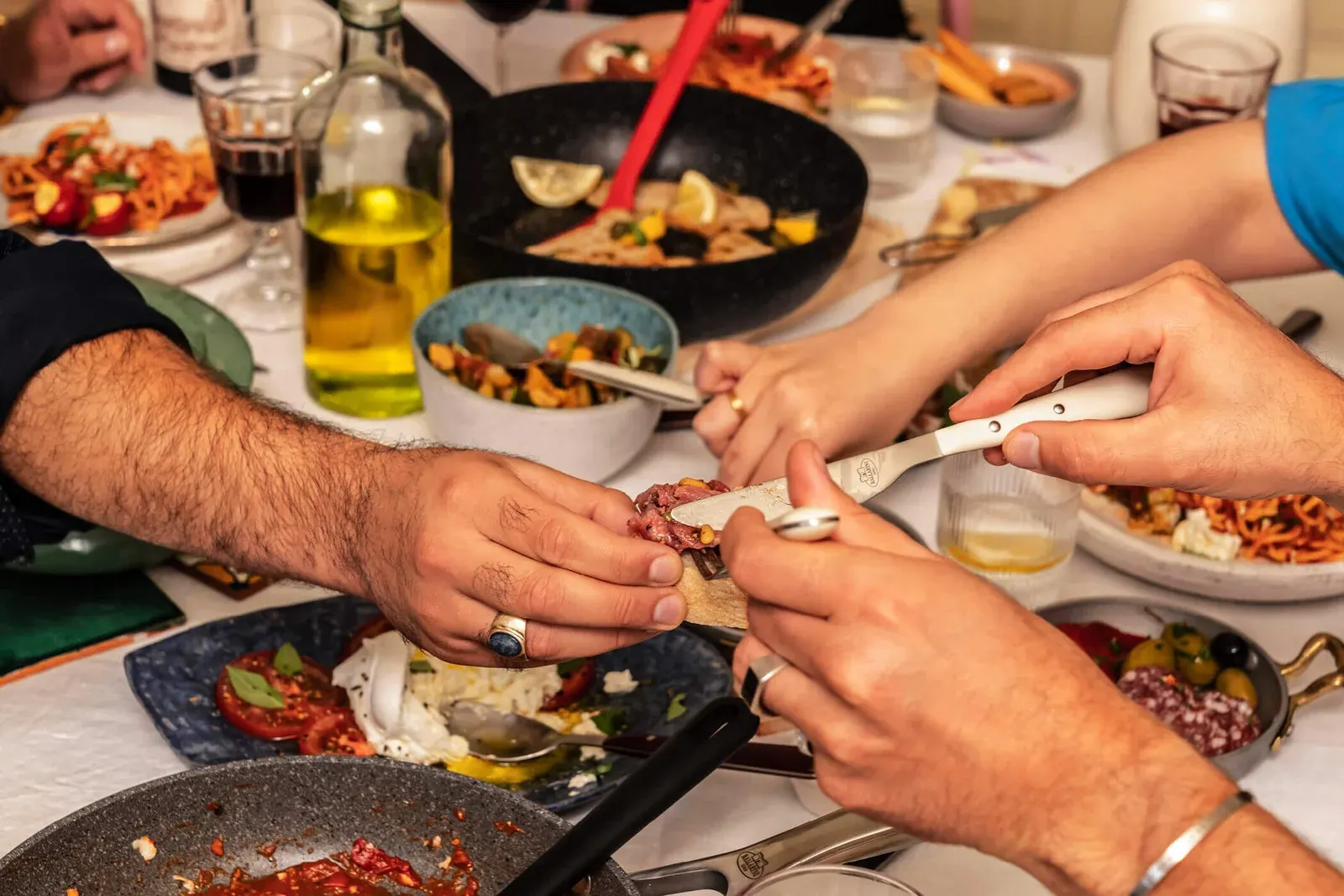 Hands reaching across a table of shared dishes at a Ballarini lunch